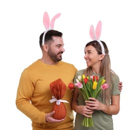 Photo of Easter celebration. Happy couple with bunny ears, tulip flowers and wrapped egg isolated on white