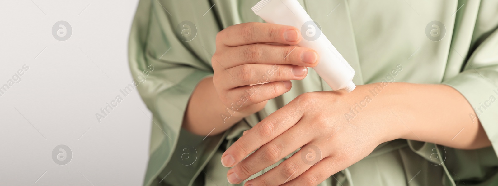 Image of Woman applying cream onto hand, closeup view. Banner design