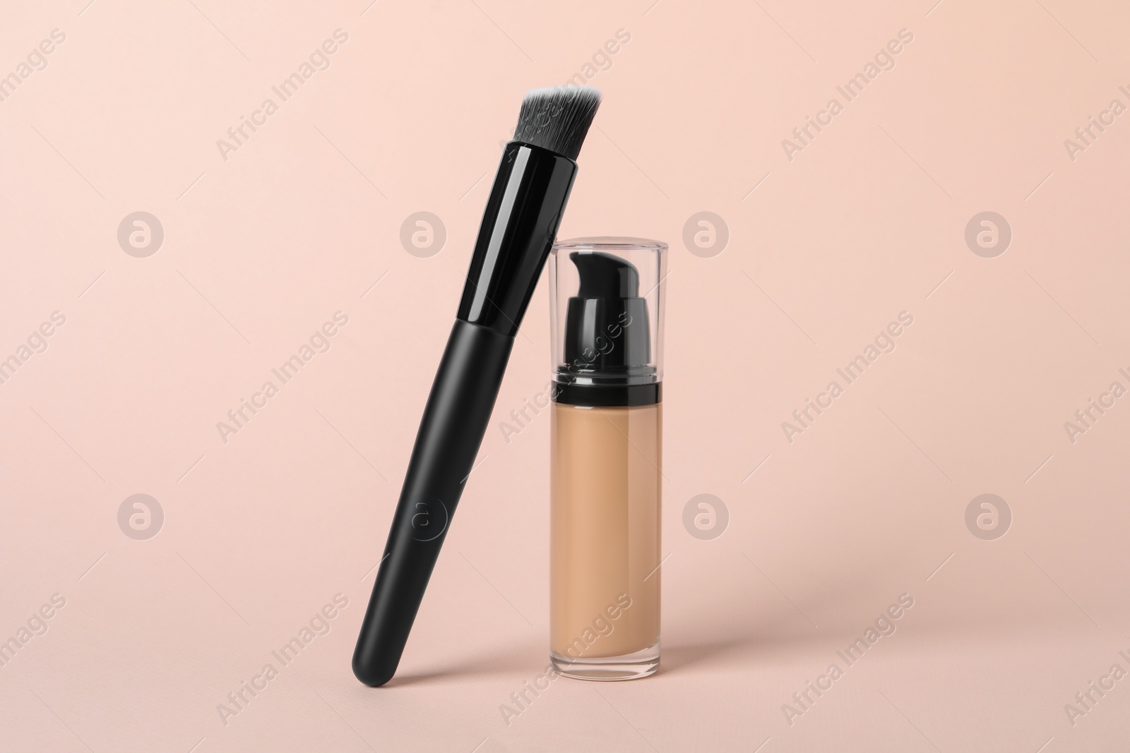 Photo of Bottle of skin foundation and brush on beige background. Makeup product