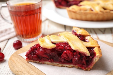 Photo of Slice of delicious fresh cherry pie on wooden board, closeup