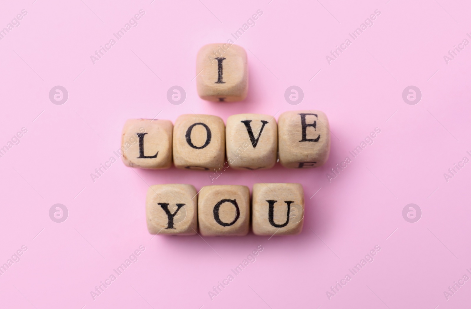 Photo of Phrase I Love You made of wooden cubes on pink background, flat lay