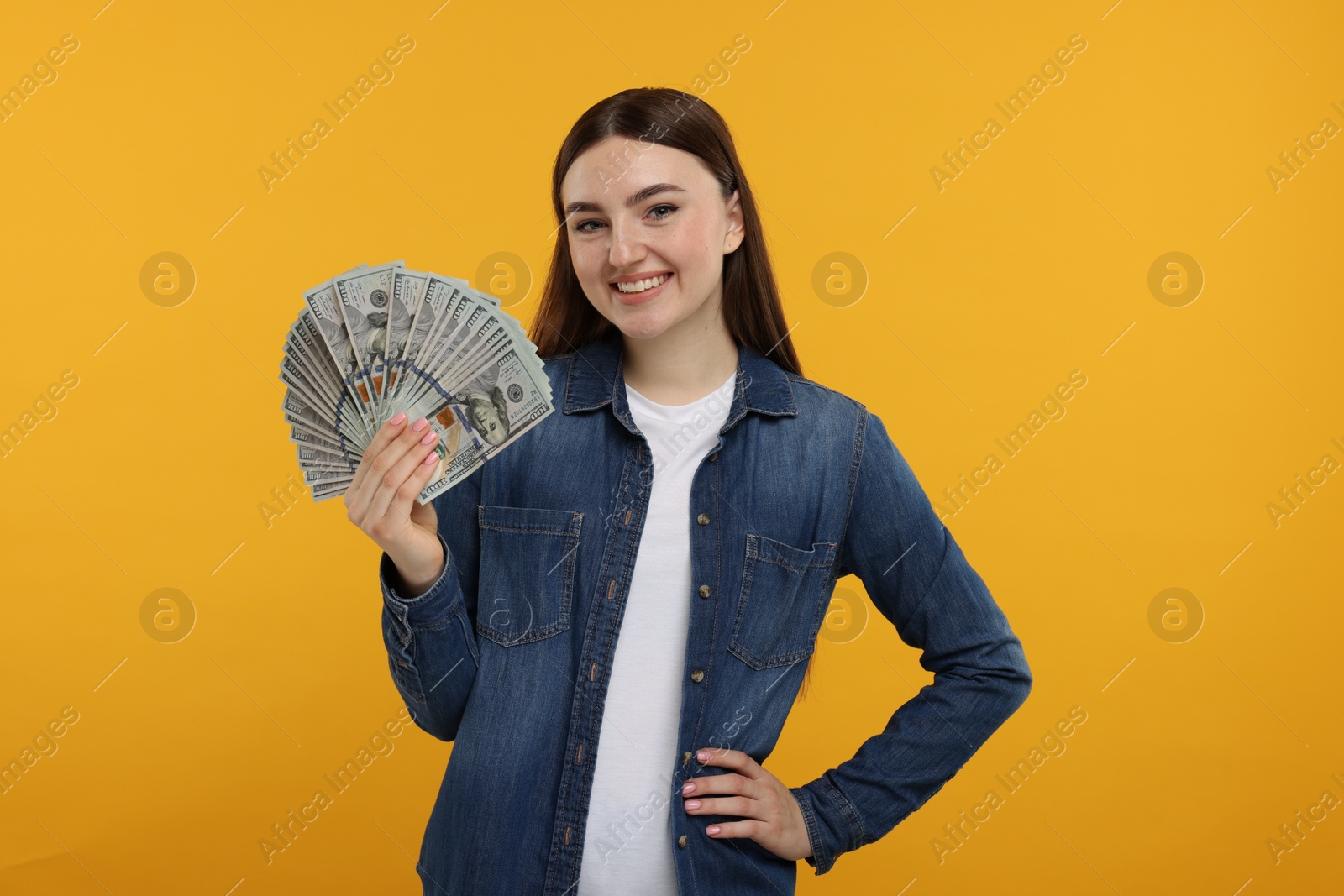 Photo of Happy woman with dollar banknotes on orange background