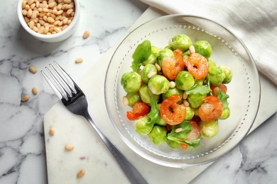 Photo of Bowl of delicious salad with Brussels sprouts and shrimps on marble table, top view
