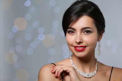 Photo of Beautiful woman with elegant jewelry on blurred background. Space for text