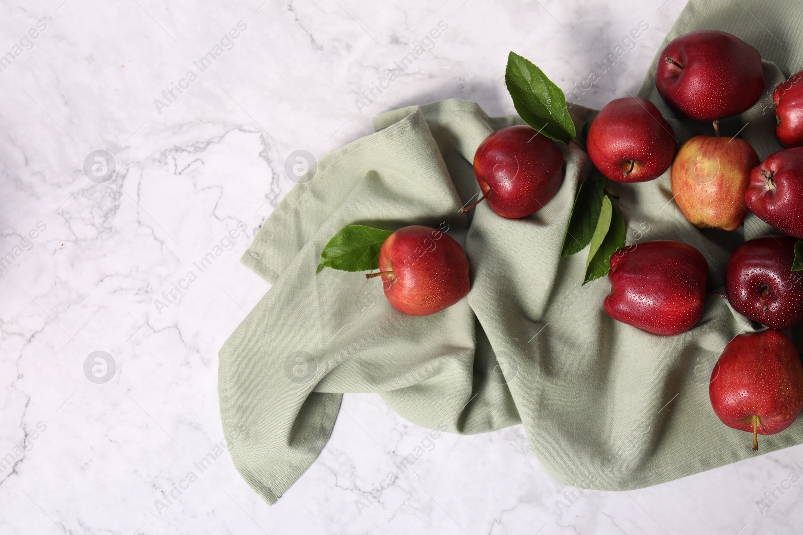 Photo of Fresh ripe red apples with leaves on white marble table, flat lay. Space for text