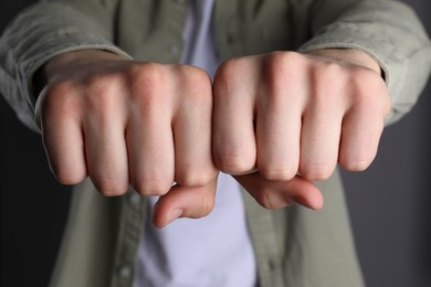 Photo of Man showing fists with space for tattoo on grey background, closeup