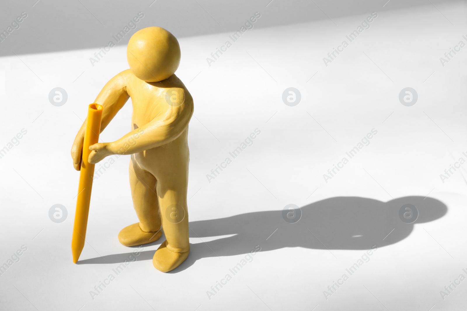 Photo of Yellow plasticine human figure with wax pencil on white background, space for text