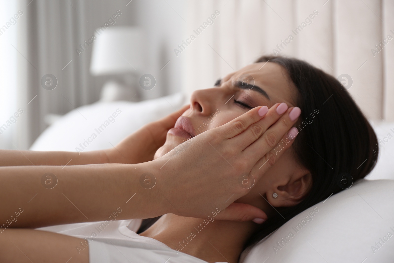 Photo of Young woman suffering from migraine in bed at home, closeup