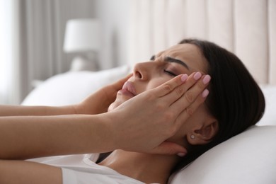 Young woman suffering from migraine in bed at home, closeup