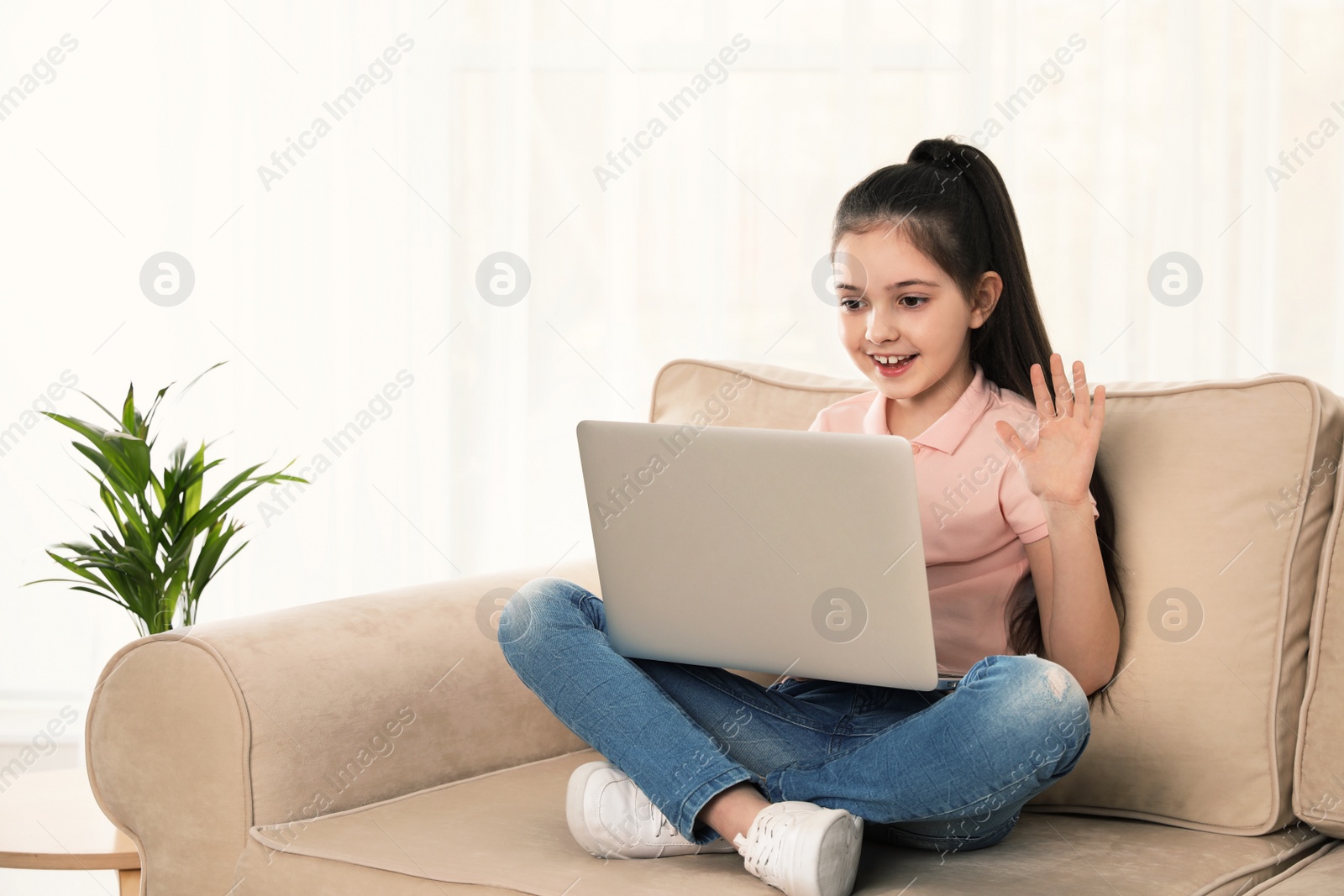 Photo of Little girl using video chat on laptop at home