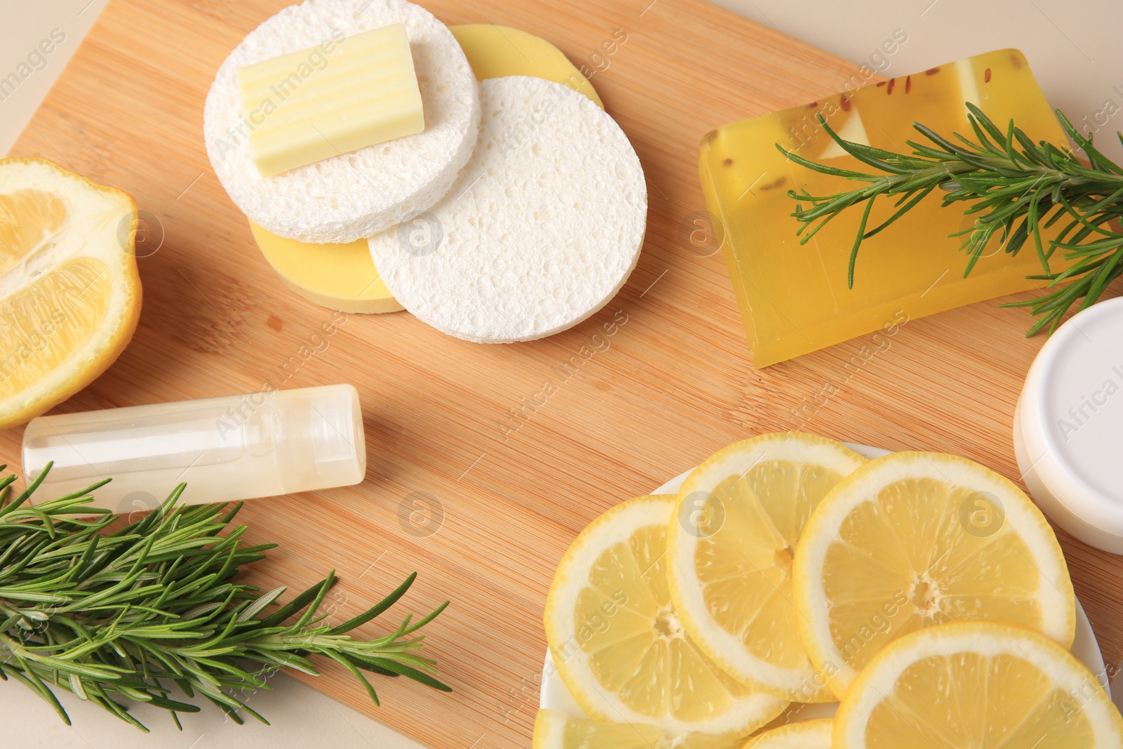 Photo of Lemon face cleanser. Fresh citrus fruits, rosemary and personal care products on wooden board, above view