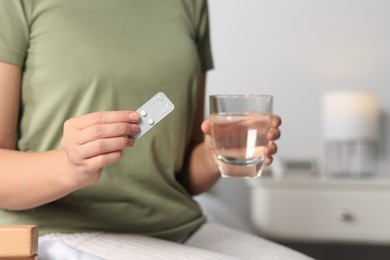 Photo of Woman taking emergency contraception pill in bedroom, focus on hand