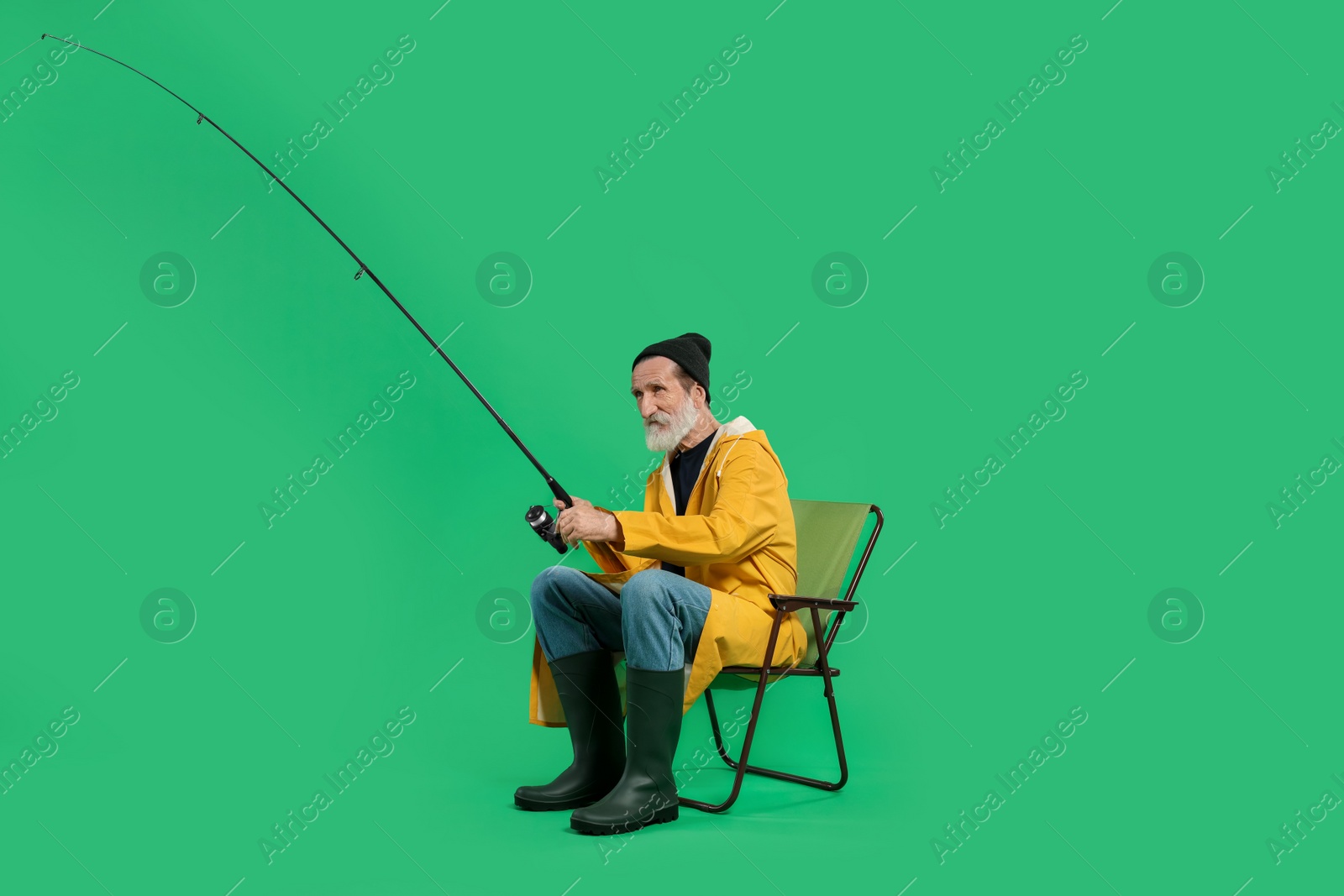 Photo of Fisherman with rod on chair against green background