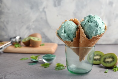 Photo of Composition with delicious spirulina ice cream cones in glass on table against grey background. Space for text