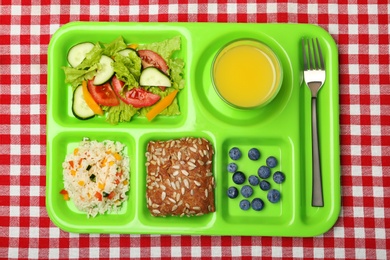 Photo of Serving tray with healthy food on tablecloth, top view. School lunch