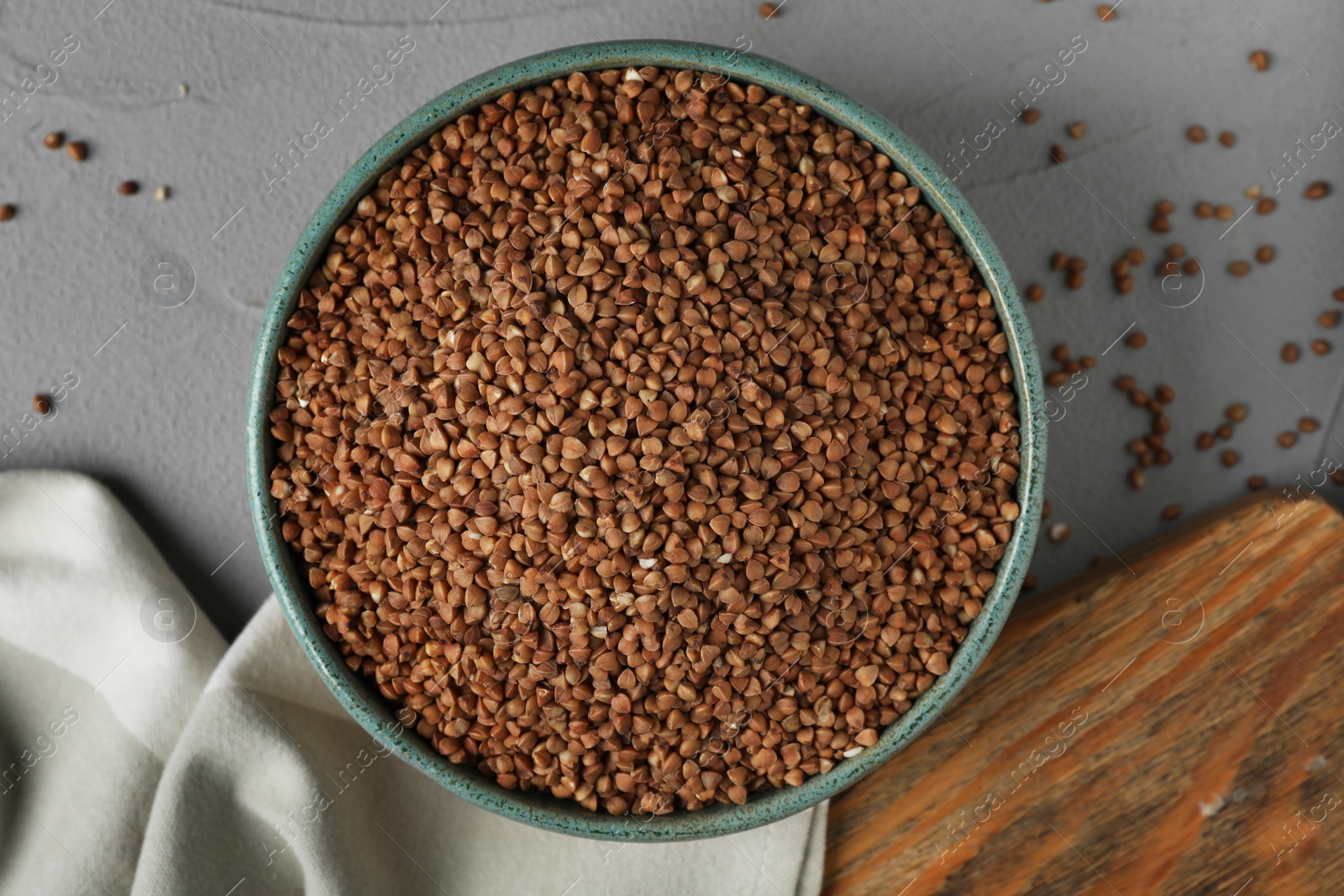 Photo of Uncooked buckwheat in bowl on table, flat lay