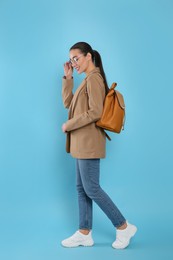 Photo of Beautiful young woman with stylish leather backpack on turquoise background