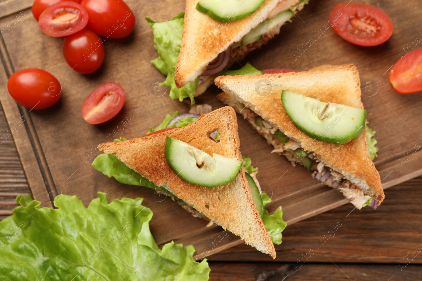 Photo of Delicious sandwiches with tuna and vegetables on wooden table, flat lay