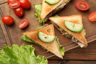 Delicious sandwiches with tuna and vegetables on wooden table, flat lay
