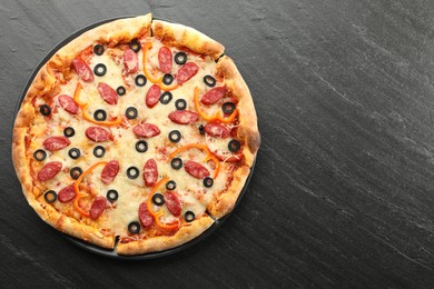 Tasty pizza with cheese, dry smoked sausages, olives and pepper on grey table, top view. Space for text