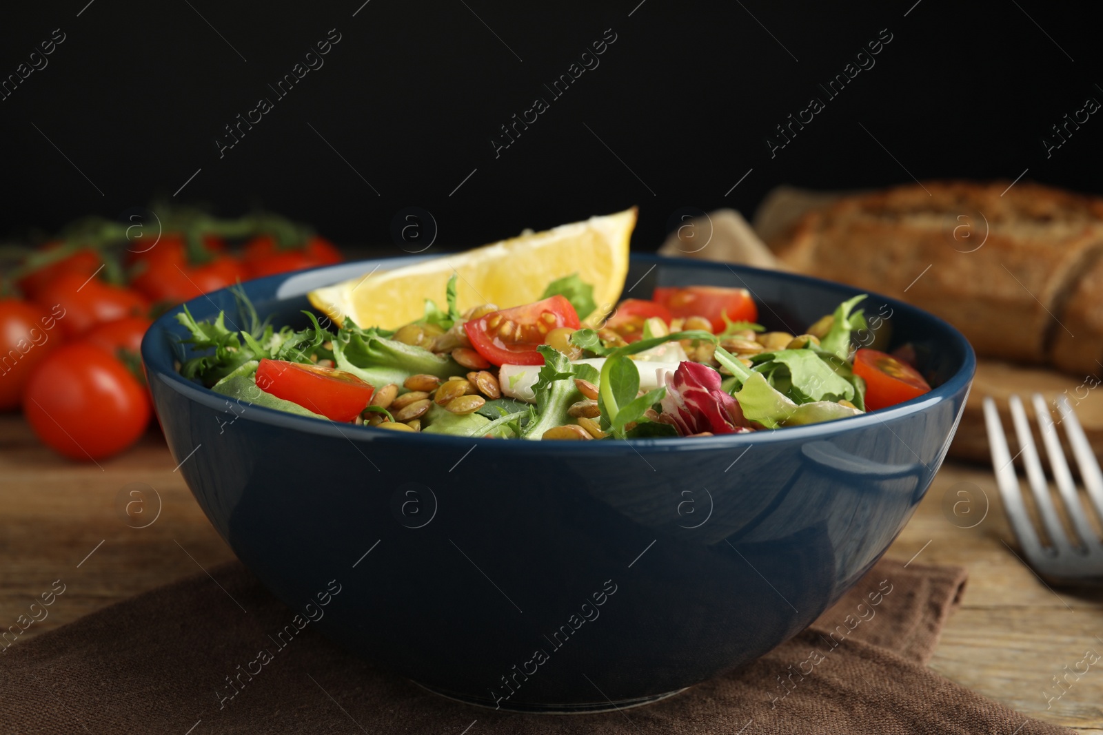 Photo of Delicious salad with lentils and vegetables on wooden table