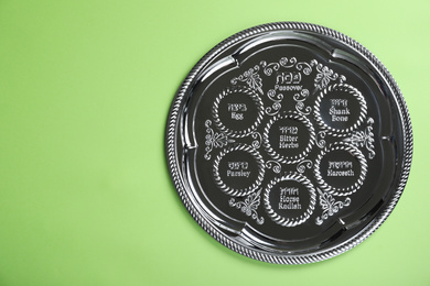 Photo of Passover Seder plate (keara) on light green background, top view with space for text. Pesah celebration