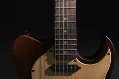 Photo of Modern electric guitar in darkness, closeup view