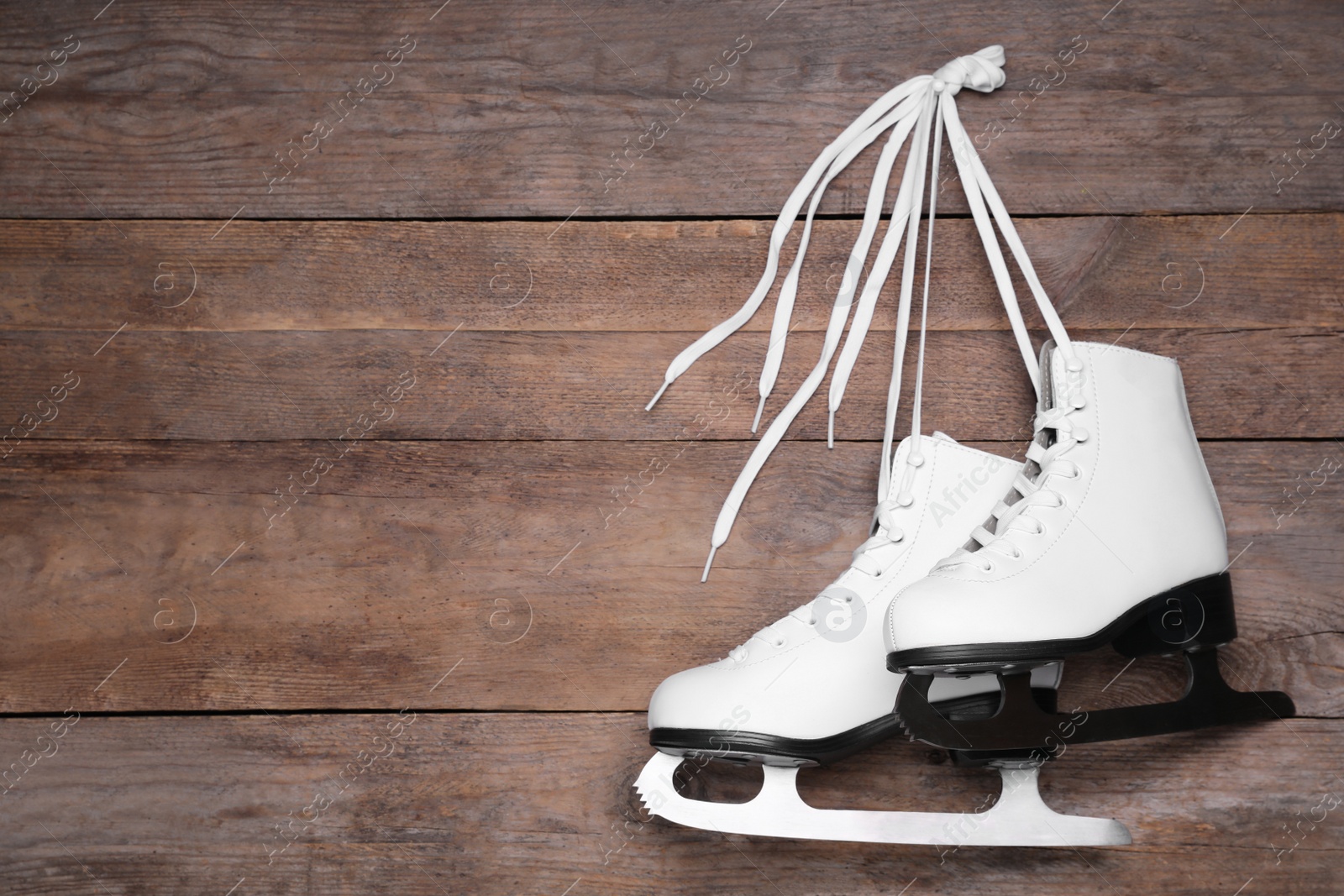 Photo of Pair of skates hanging wooden background. Space for text