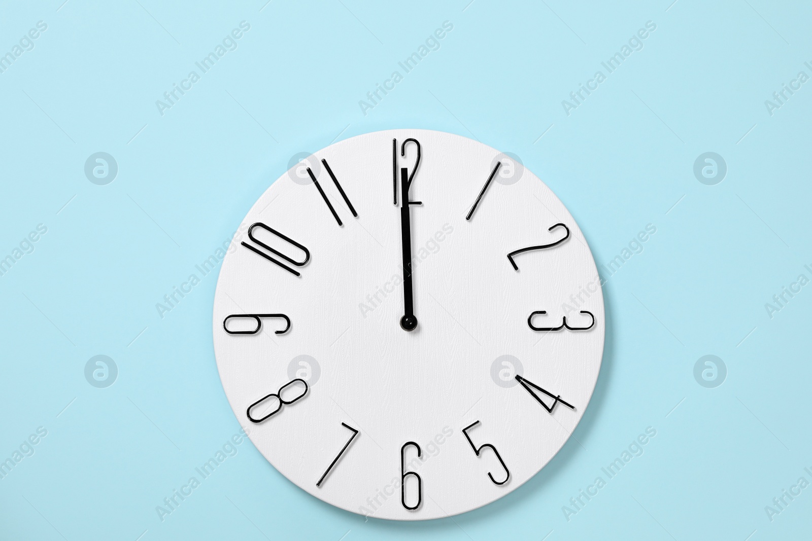 Photo of Stylish analog clock hanging on light blue wall