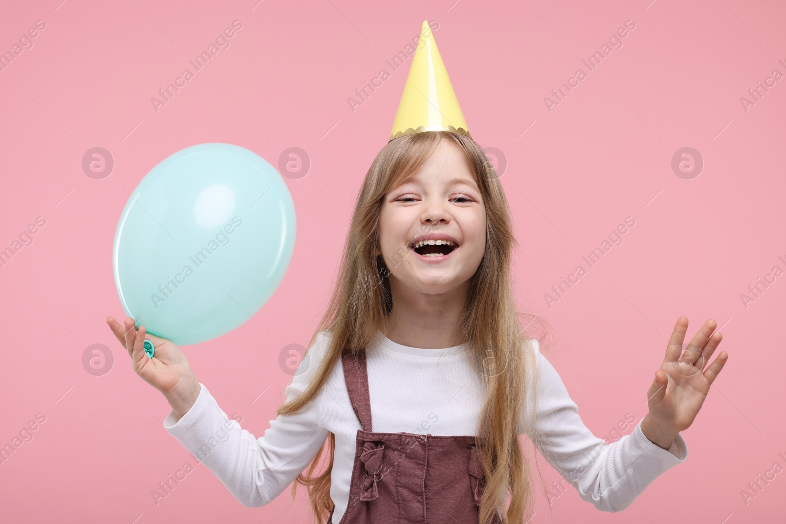 Photo of Cute little girl in party hat with balloon on pink background