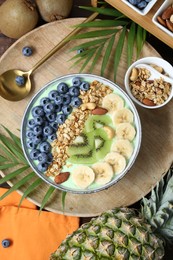 Photo of Tasty smoothie bowl with fresh fruits and oatmeal served on table, flat lay