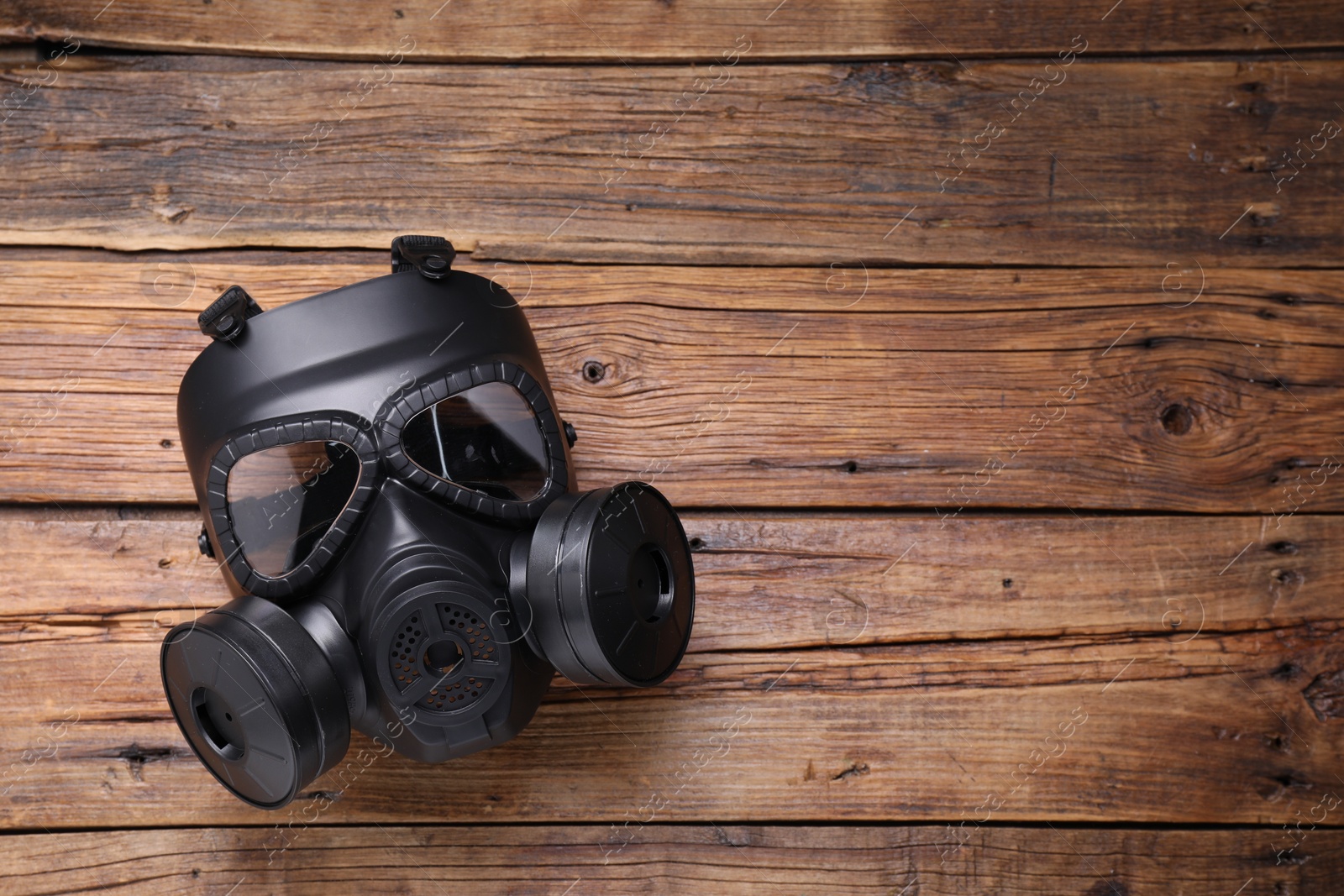 Photo of One gas mask on wooden background, top view. Space for text