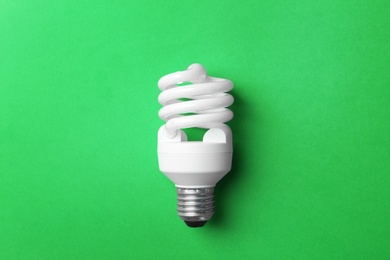 New fluorescent lamp bulb on green background, top view