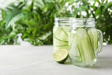 Photo of Mason jars of fresh cucumber water on table. Space for text