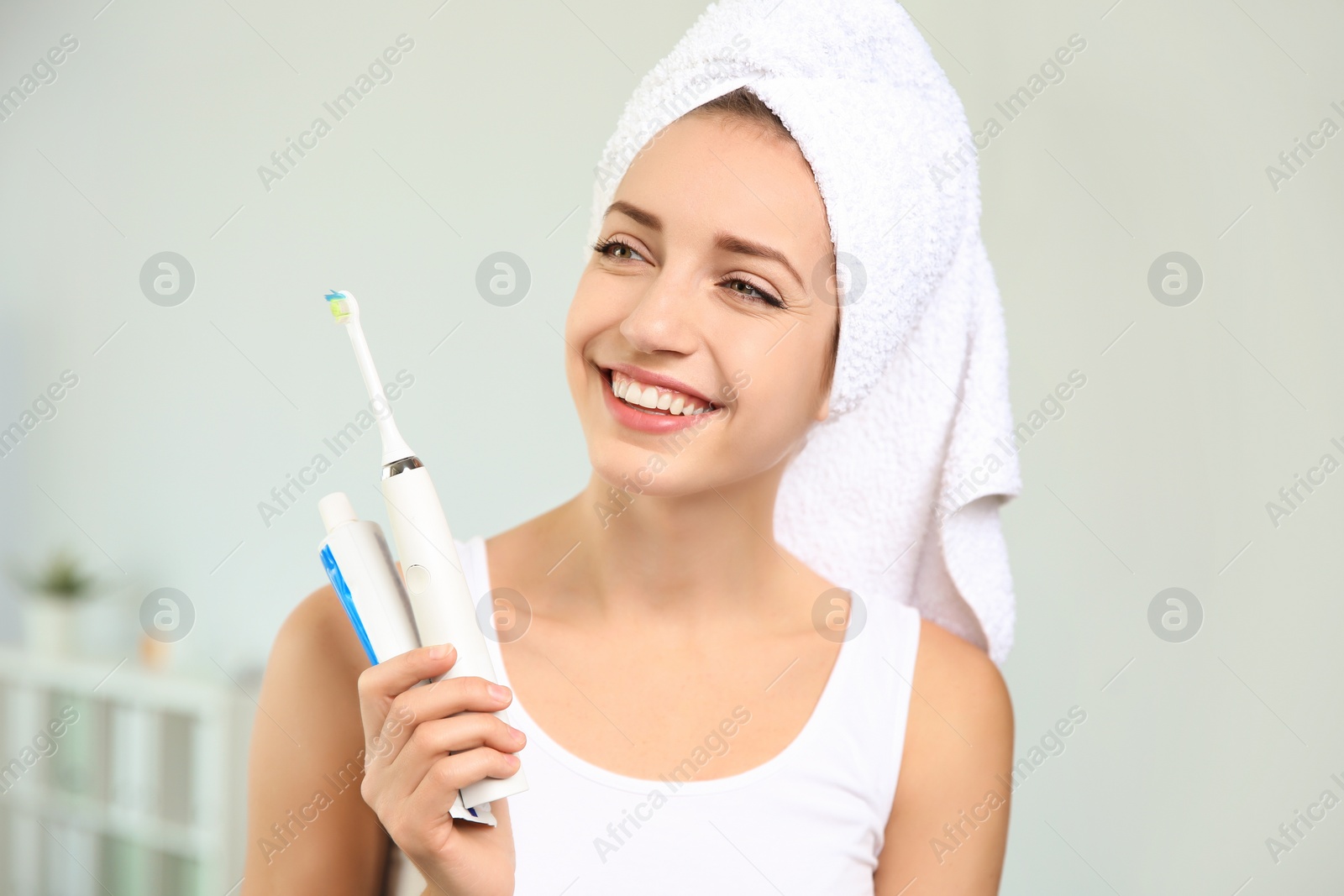 Photo of Portrait of young woman with electric toothbrush and paste on blurred background