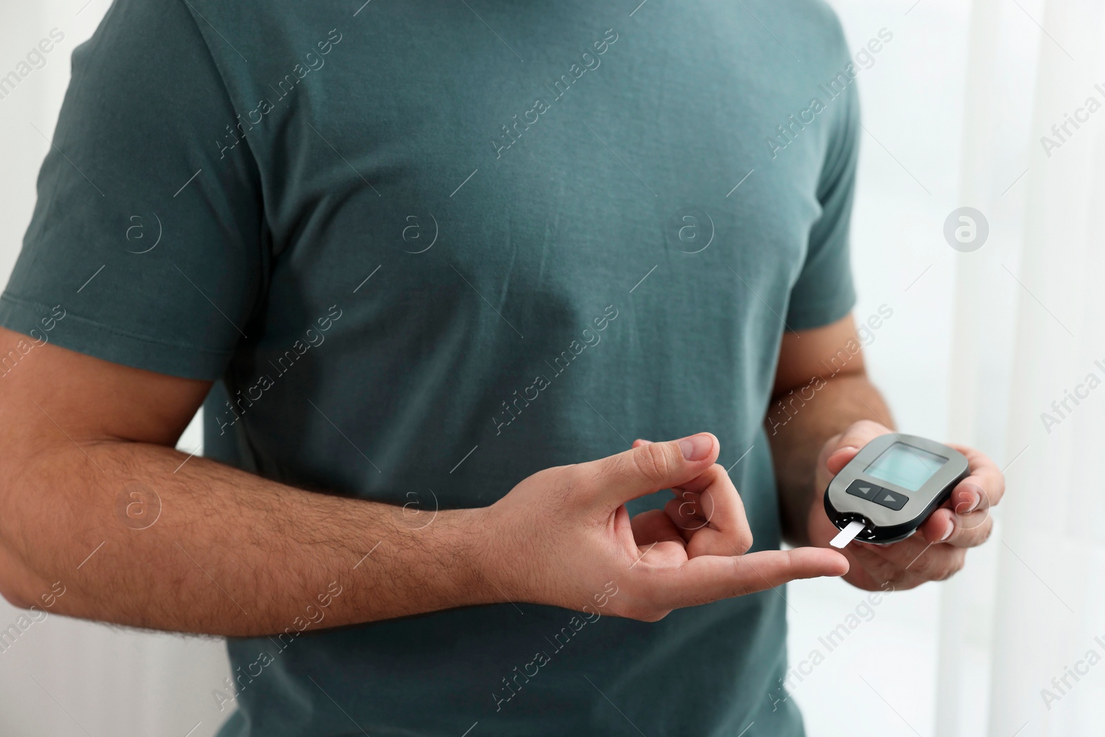 Photo of Diabetes test. Man checking blood sugar level with glucometer at home, closeup