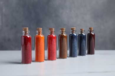 Glass bottles with different food coloring on white marble table