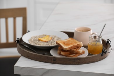 Wooden tray with delicious breakfast on white marble table