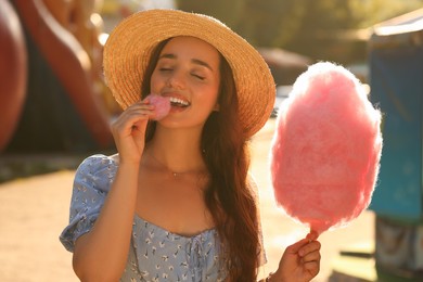 Photo of Beautiful young woman eating cotton candy outdoors on sunny day