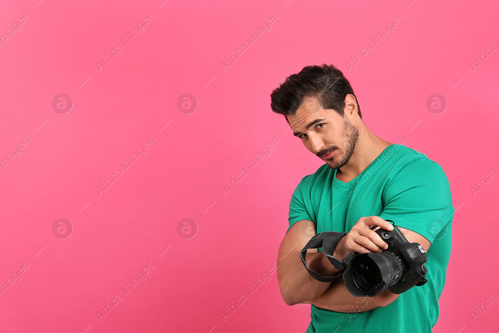 Photo of Young photographer with professional camera on pink background. Space for text