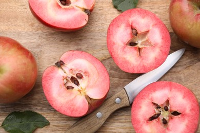 Tasty apples with red pulp, leaves and knife on wooden board, flat lay