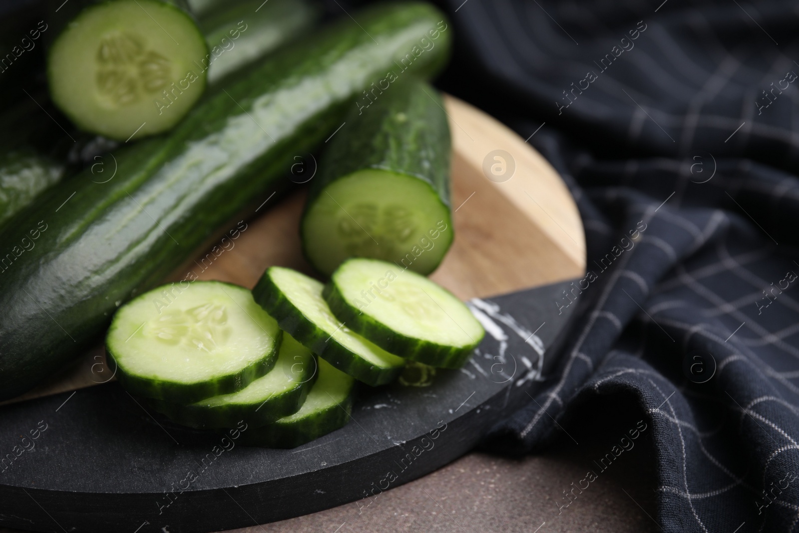 Photo of Fresh whole and cut cucumbers on table, closeup