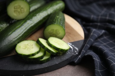 Photo of Fresh whole and cut cucumbers on table, closeup