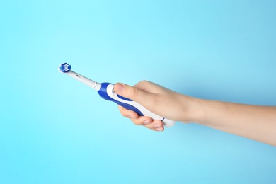 Photo of Woman holding electric toothbrush against color background