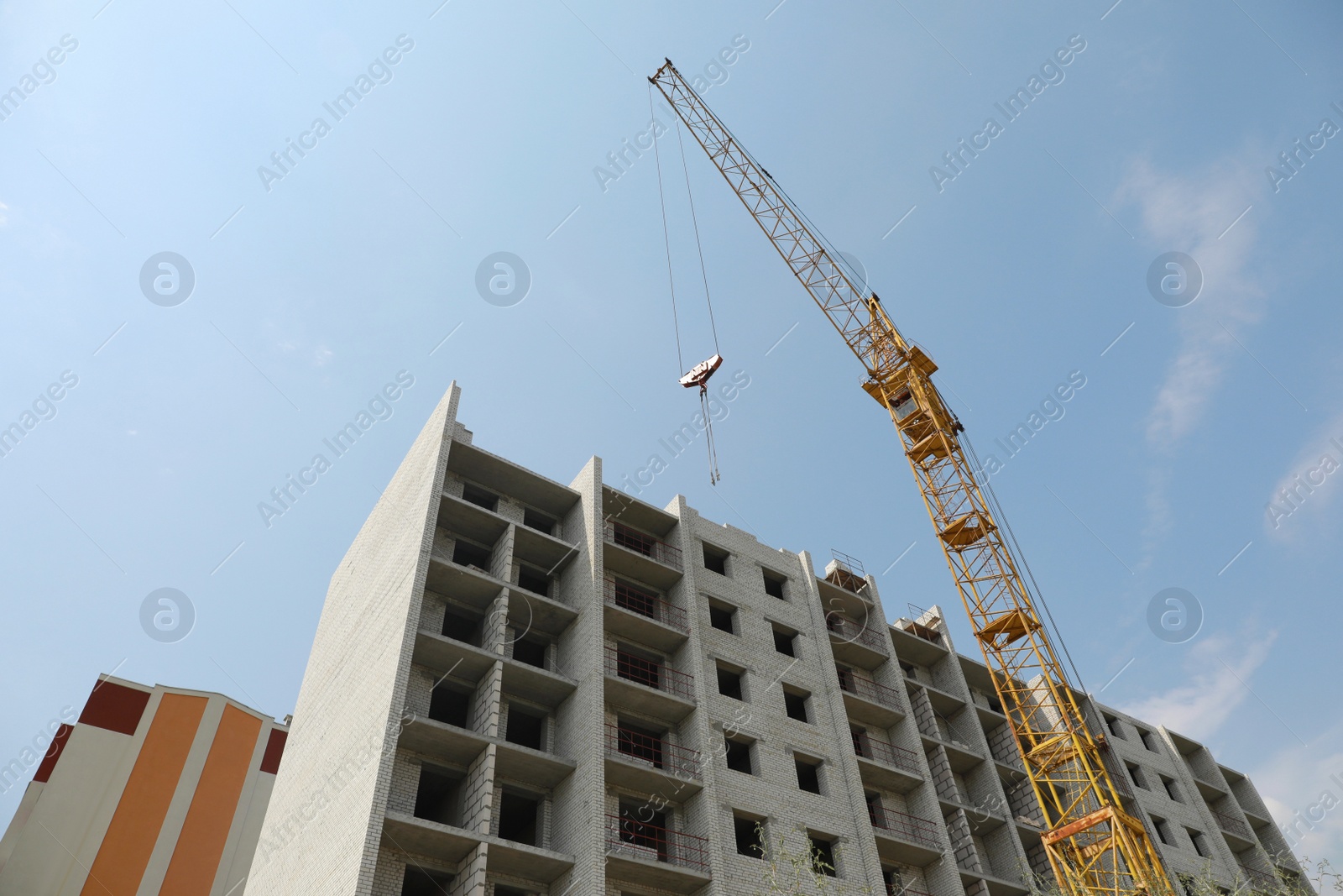 Photo of Unfinished building and construction crane outdoors, low angle view