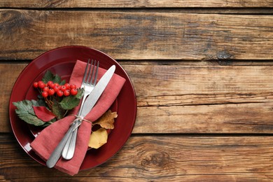 Festive table setting with autumn leaves and ashberries on wooden background, top view. Space for text