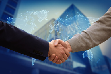 Image of Closeup view of partners shaking hands and world map. Business values