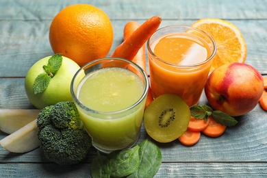 Glasses of delicious juices and fresh ingredients on blue wooden table