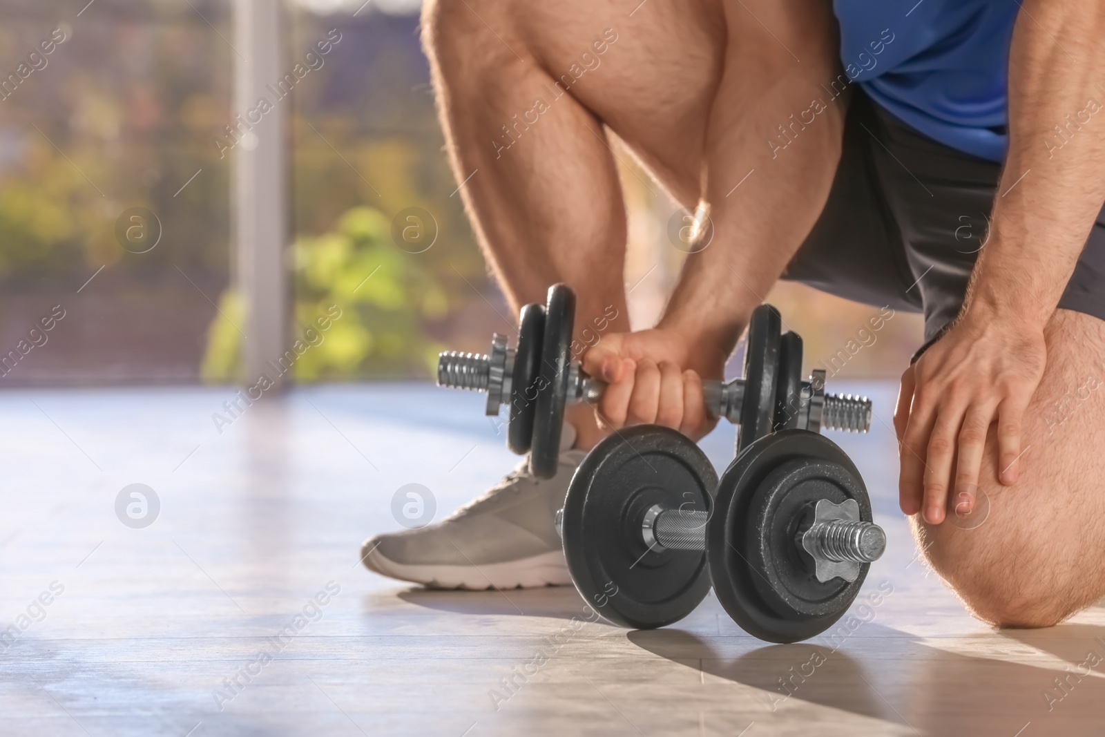 Photo of Male athlete with adjustable dumbbells indoors. Space for text