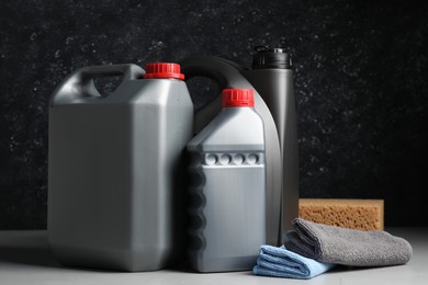 Photo of Car cleaning products, canisters with motor oil and microfiber fabric on light grey table